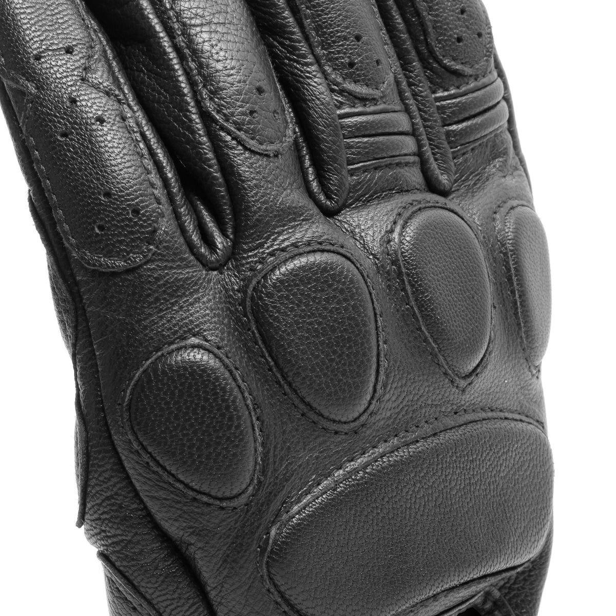 DAINESE BLACKJACK UNISEX GLOVES 手腕束帶特寫，可見金色DAINESE 1972 GP&Road復古標籤壓印於黑色皮革上，手背通氣孔與縫線工藝清晰可見