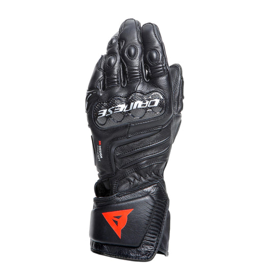 DAINESE CARBON 4 LONG LEATHER GLOVES 全黑手套手背朝上展示，可見碳纖維指關節護具與DAINESE品牌字樣，山羊皮革縫製質感清晰，競技長手套黑色配色