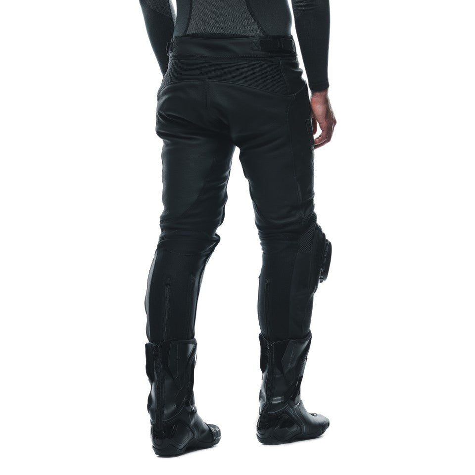 DAINESE DELTA 3 PERF.LEATHER PANTS 背面視角特寫，展示打孔皮褲搭配車靴的完整版型，可見膝蓋護具卡榫、腰際羅紋束帶與後方口袋車縫細節，義大利原廠Tutu小牛皮革局部打孔製賽道皮褲，透氣散熱佳