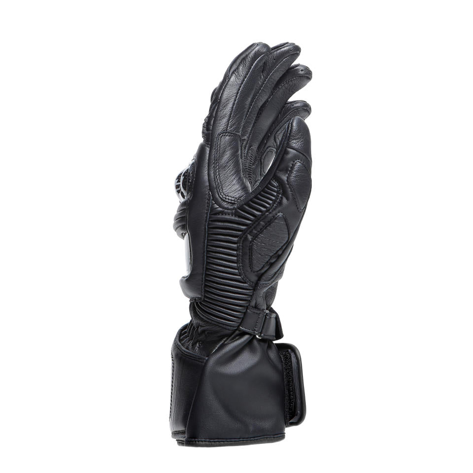 DAINESE DRUID 4 LEATHER GLOVES 側面視角展示，可見預彎曲手指與四向彈性伸縮插件立體結構，指節護具與手腕可調式束帶清晰可見，黑黑炭灰配色競技長手套側面細節照