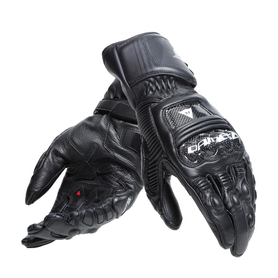 DAINESE DRUID 4 LEATHER GLOVES 一雙手套交疊陳列，可見碳纖維指節護具與DAINESE品牌標誌，黑黑炭灰配色山羊皮革縫製質感，競技型長手套成對展示照