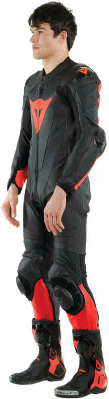 DAINESE LAGUNA SECA 5 1PC PERF. LEATHER SUIT 黑/螢光紅打洞連身賽車皮衣側面實穿照，展示立體膝滑塊與腿部剪裁曲線，車手側身站姿呈現版型細節