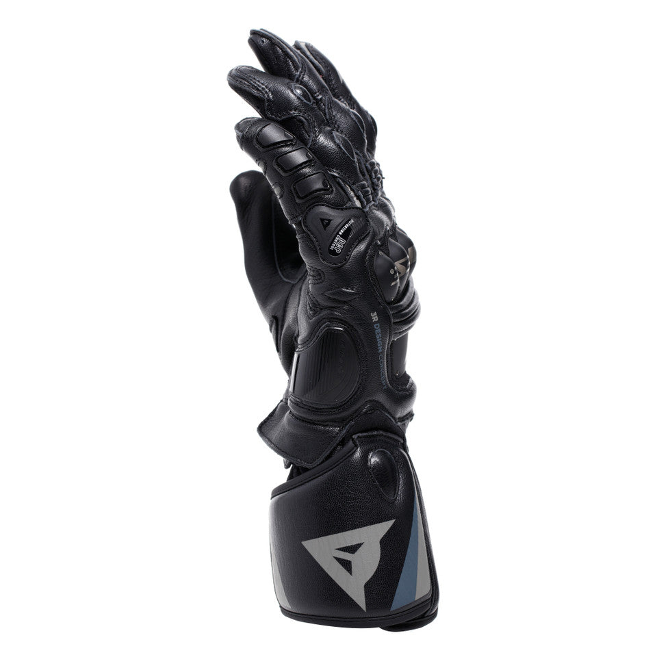 DAINESE STEEL-PRO GLOVES BLACK/ANTHRACITE 側面視角，展示指關節鎢鋼護具立體輪廓與可調式魔鬼氈袖口束帶，山羊皮革縫製質感清晰可見，黑/炭灰配色義大利原廠賽道皮革手套