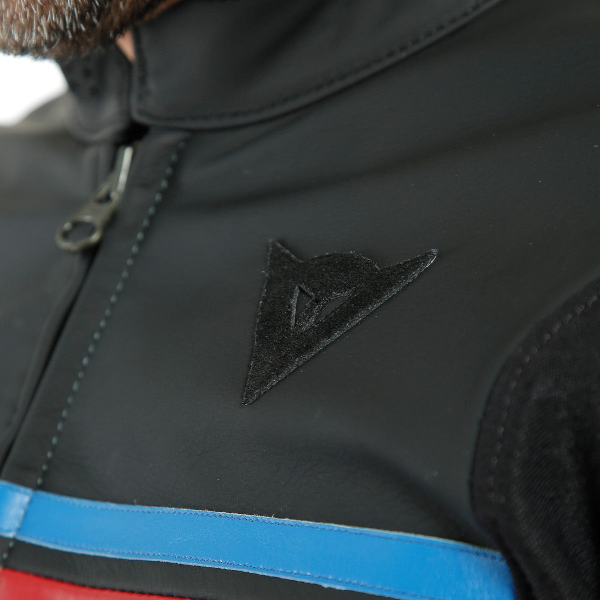 DAINESE HF 3 LEATHER JACKET 胸口DAINESE三角標誌與紅藍條紋特寫，消光牛皮革質感與車縫細節